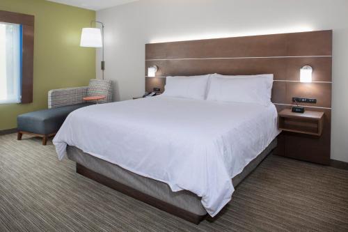 ein Hotelzimmer mit einem großen Bett und einem Stuhl in der Unterkunft Holiday Inn Express & Suites - King George - Dahlgren, an IHG Hotel in Alden