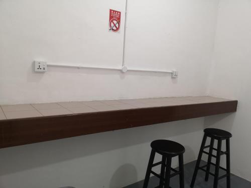 a counter with two stools in front of a wall at SPOT ON 90735 night Stayin in Sibu