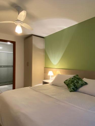 a bedroom with a white bed with a green wall at Pousada Matitaterê in Teresópolis