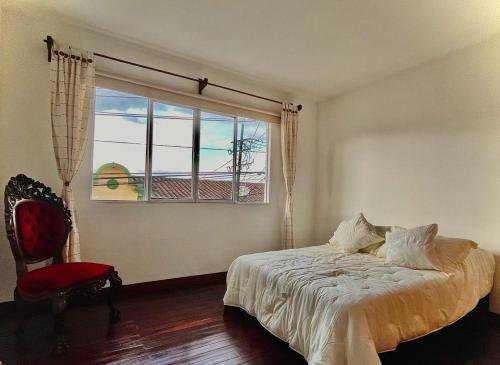 um quarto com uma cama, uma janela e uma cadeira em Apartamento Colonial em Santa Rosa de Cabal