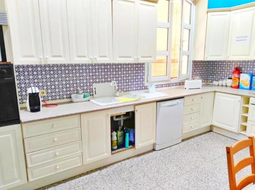 cocina con armarios blancos, fregadero y lavavajillas en Apartamento El Duque - Plaza de las Tendillas en Córdoba