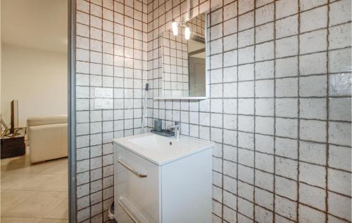 Baño de azulejos blancos con lavabo y espejo en Beautiful Apartment In Ghisonaccia With Kitchen, en Ghisonaccia