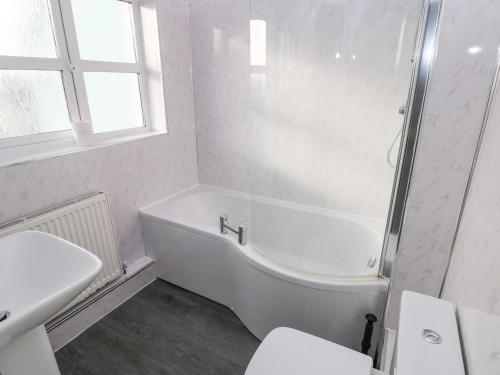 Baño blanco con bañera y lavamanos en Driftwood House, en Saundersfoot