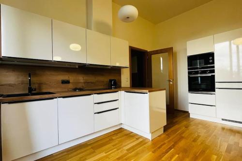 cocina con armarios blancos y suelo de madera en Apartment Holesovice, garden, garage, en Praga
