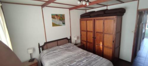 1 dormitorio con 1 cama y armario de madera en Ellas y Marú en La Paloma