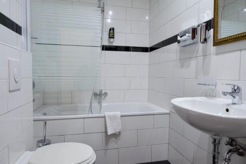 a bathroom with a sink and a toilet and a tub at Hotel City Panorama in Hannover