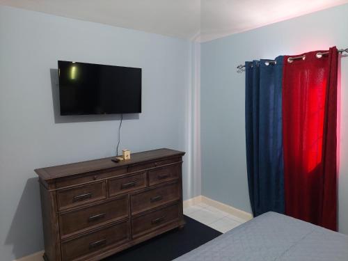 a bedroom with a dresser and a television on a wall at Relax in Paradise in Montego Bay