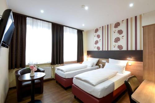 ein Hotelzimmer mit 2 Betten und einem TV in der Unterkunft Hotel City Panorama in Hannover