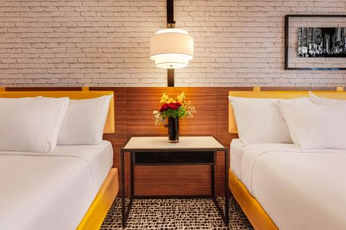 two beds in a room with a vase of flowers on a table at New York-New York in Las Vegas