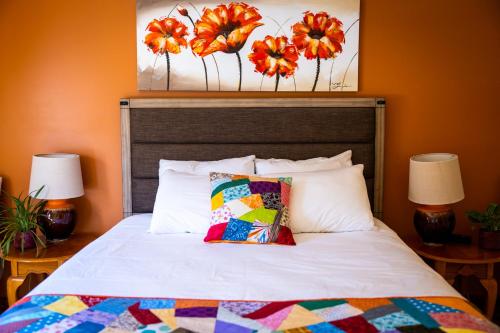 a bed with a colorful quilt and two lamps at Upper Humber Settlement a FarmStay B&B in Cormack