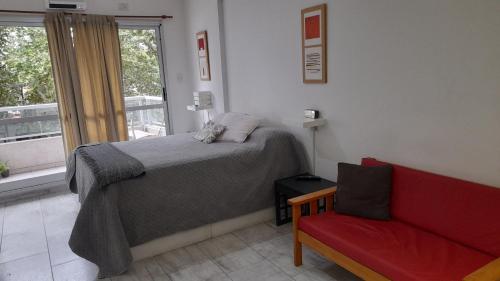 um quarto com uma cama e um sofá vermelho em Amplio monoambiente en edificio moderno em Buenos Aires