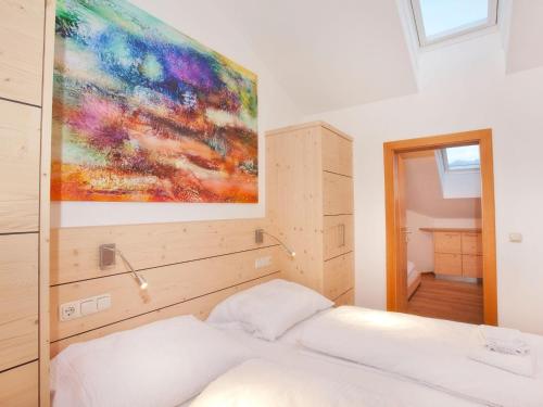 a bedroom with a white bed with a painting on the wall at Apartment in Wald im Pinzgau near Ski Lift in Wald im Pinzgau