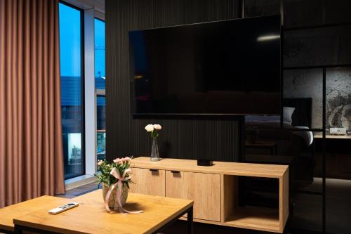 a living room with a tv and a table with flowers at Fillhus Apartments in Poznań