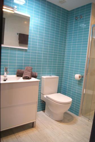 a bathroom with a toilet and a sink and blue tiles at Pomera I - BTB in Beniarbeig