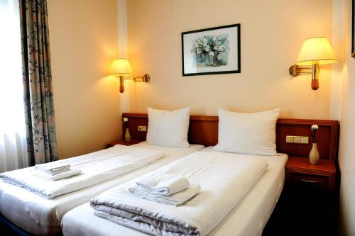 two beds in a hotel room with towels on them at Hotel Opal in Hannover