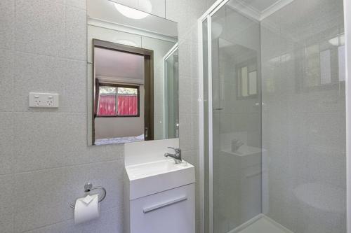 a bathroom with a sink and a glass shower at Cape Hillsborough Nature Tourist Park in Seaforth