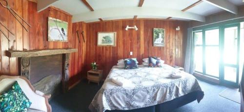 a bedroom with a bed in a room with wooden walls at Blackfern Lodge in Waimiha