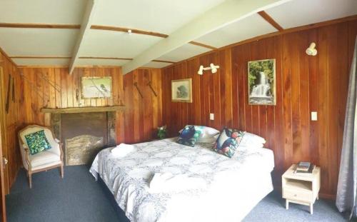 a bedroom with a bed in a wooden wall at Blackfern Lodge in Waimiha