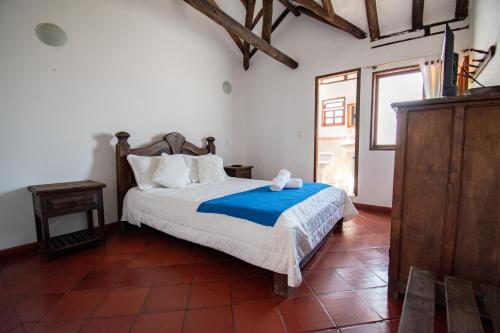 a bedroom with a bed with a blue blanket at Hotel Villa Luna in Villa de Leyva