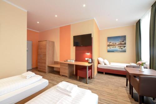 a hotel room with two beds and a desk at Alexander Business Hotel Hannover City in Hannover