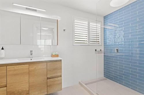 a bathroom with a sink and a shower with blue tiles at Aqua Vista in Airlie Beach