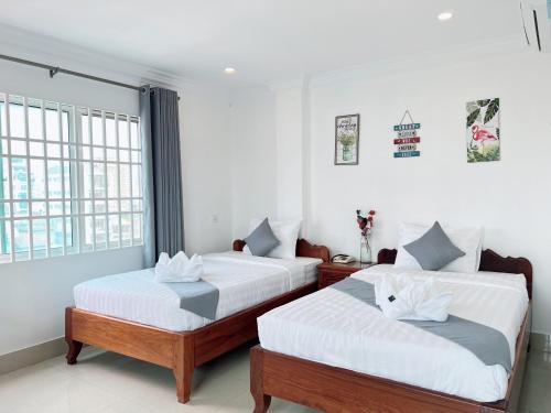 two beds in a room with white walls and windows at White Corner Hotel in Phnom Penh