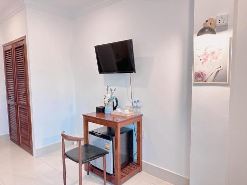 a room with a table and a chair and a tv on a wall at White Corner Hotel in Phnom Penh