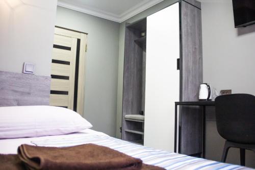 a bedroom with a bed and a chair and a mirror at Hotel Tahar in Almaty