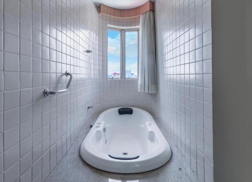 a white tiled bathroom with a toilet in the floor at Hotel Hot Springs 528 in Caldas Novas