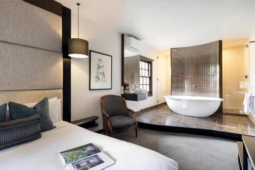 a bedroom with a bed and a bath tub in a bathroom at Mineral Springs Hotel Hepburn in Hepburn Springs