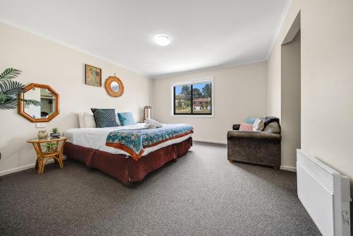 a bedroom with a bed and a mirror and a couch at Jasper 4 in Jindabyne