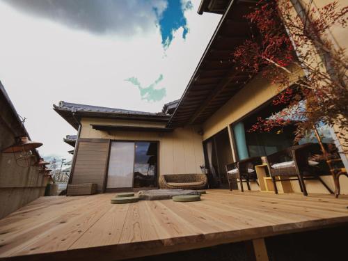 una terraza de madera con sillas en una casa en 古民家ゲストハウス CHACHACHA AWAJI en Awaji