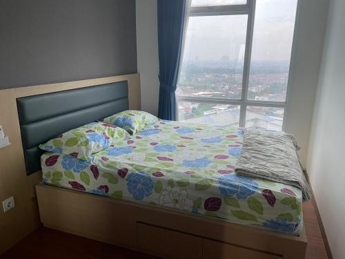 ein Bett in einem Schlafzimmer mit einem großen Fenster in der Unterkunft Luxury Apartemen Grand Lagoon Sungkono Surabaya in Dukuhpakis