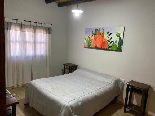 1 dormitorio con 1 cama y una pintura en la pared en Cabaña La Soñada en Tilcara