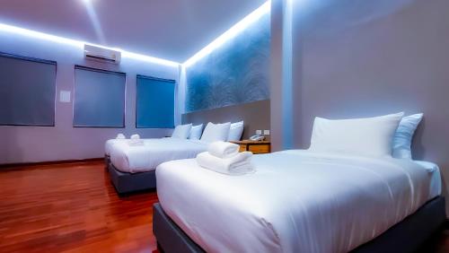 two beds in a hotel room with blue lighting at The Riva Vientiane Hotel in Vientiane