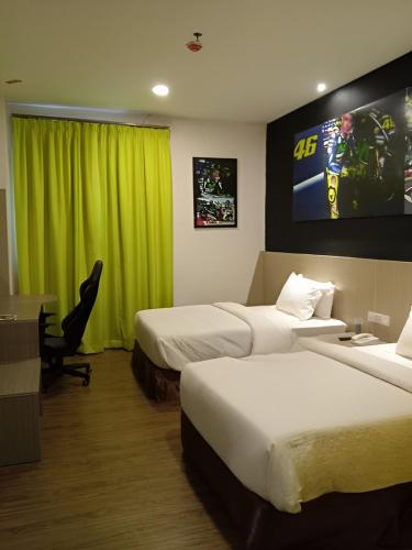 a hotel room with two beds and a flat screen tv at Hype Motorsport Hotel Nilai in Nilai