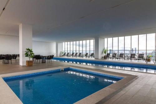 une grande piscine avec des chaises et des tables dans un bâtiment dans l'établissement Moderno Bien Ubicado , Piscina A97c, à Guadalajara