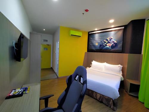 a bedroom with a bed and a tv and a chair at Hype Motorsport Hotel Nilai in Nilai