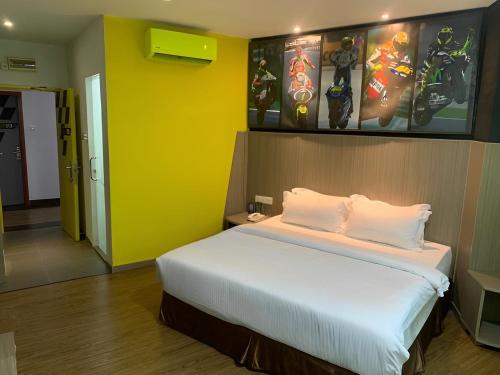 a bedroom with a large bed with a yellow wall at Hype Motorsport Hotel Nilai in Nilai