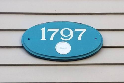 a blue sign on the side of a house at Charming Townhouse in Historic Town near Boston. in Dedham