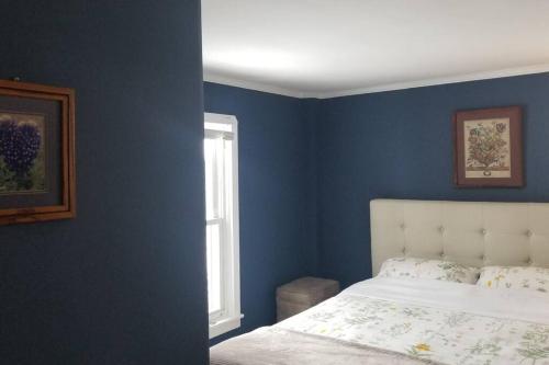 a blue bedroom with a bed and a window at Charming Townhouse in Historic Town near Boston. in Dedham