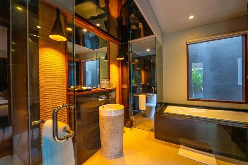 a bathroom with a shower and a tub and a sink at Agranusa Signature Villa Nusa Dua in Nusa Dua