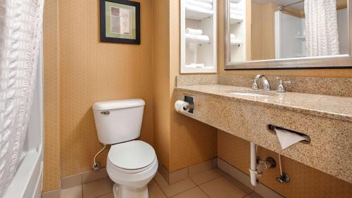 a bathroom with a toilet and a sink and a mirror at Best Western Windsor Inn and Suites in Danville