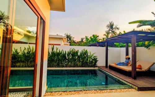 a man laying on a bed next to a swimming pool at WAKA VILLA Private Pool Resort & Spa - Adults Only in Siem Reap