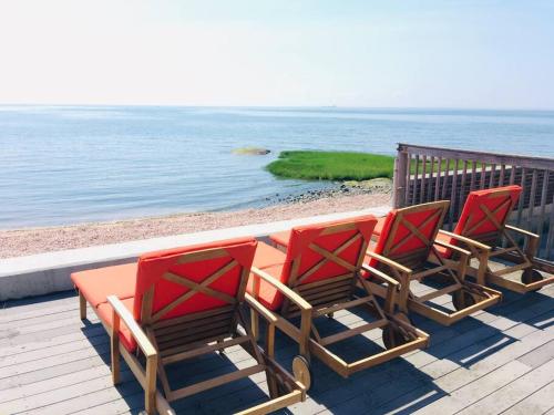 four chairs and a table on a deck overlooking the ocean at Casa al Mare Beachfront Retreat King Bed Near Yale in East Haven