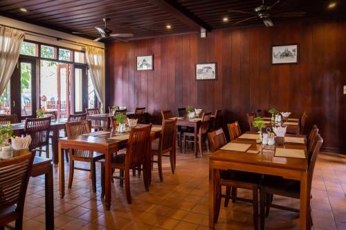 a restaurant with wooden walls and wooden tables and chairs at Sada Hotel in Luang Prabang