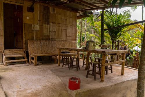 a patio with wooden tables and chairs and a house at Rain Forest Inn in Ringlet