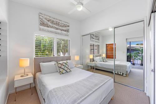 a white bedroom with two beds and a balcony at Verano Resort Noosa in Noosaville