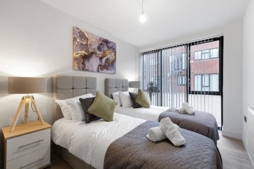 a bedroom with two beds and a large window at Infra Mews, Superb Delightful Apartments Perfect for Contractors & Long Stays, 1, 2 & 4 Bedroom, WiFi & Parking in Milton Keynes