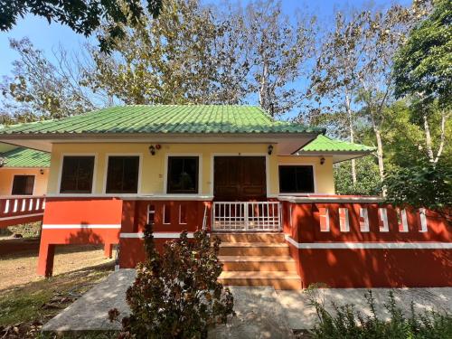 une petite maison jaune avec un toit vert dans l'établissement ViangPhing Resort, à Mae Chan